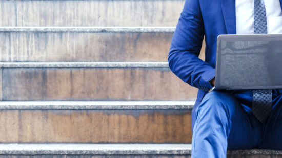 Businessman sitting on stairs and using laptop-independent contractor-gig worker economy-Shutterstock_701263531